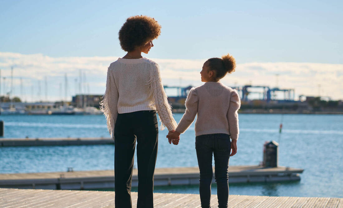 Mother and daughter hold hands while looking at each other