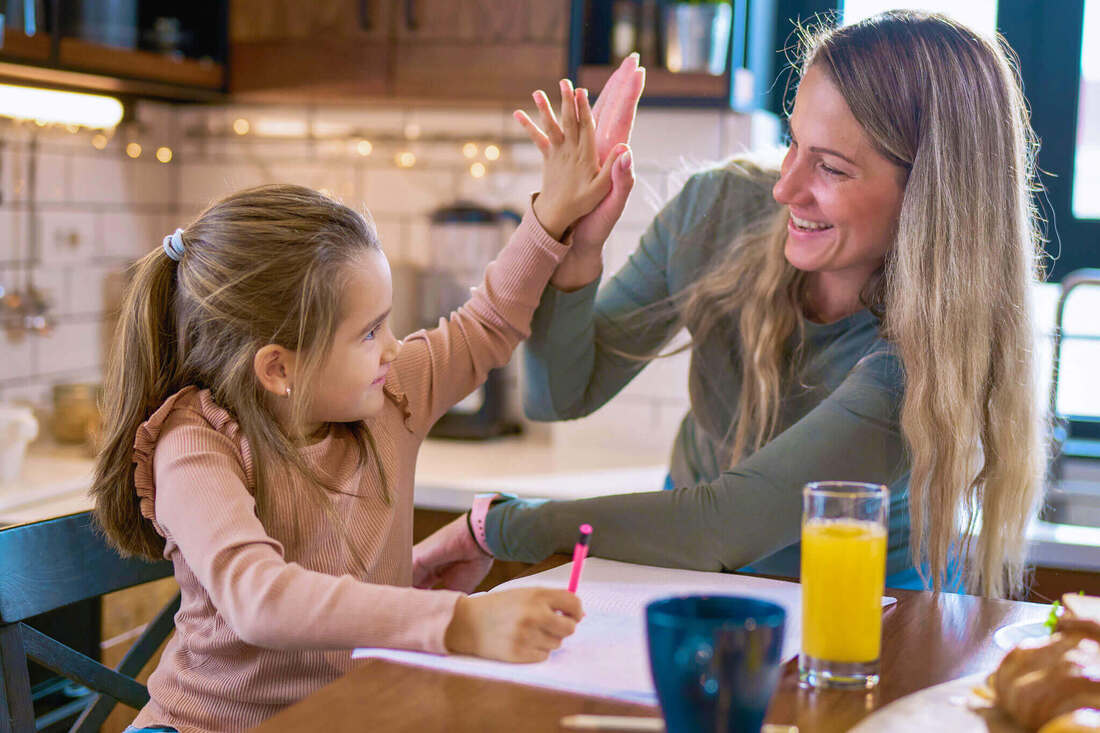 Mother and daughter high-five while doing homework